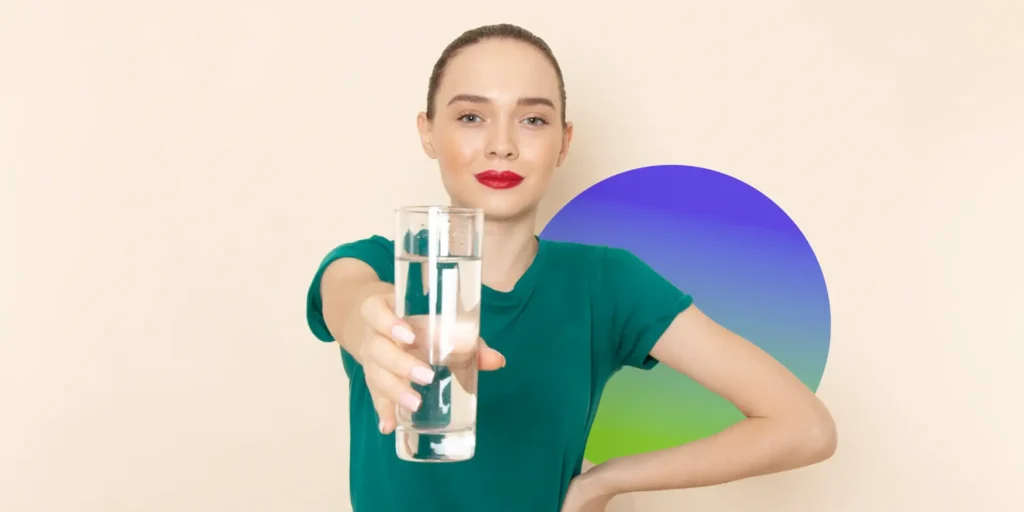 women holding a cup of water in front of ger to increase her fluid intake and protect against hydration