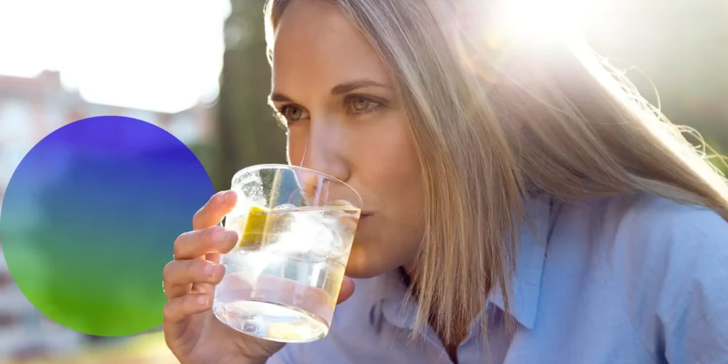 woman drinking water to hydrate and avoid a heat stroke