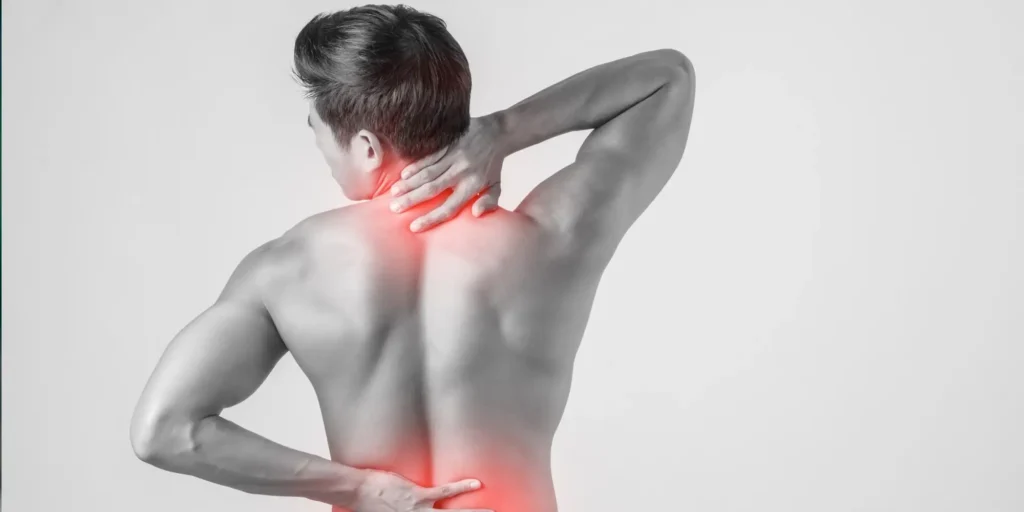 a man touching the back of his neck and lower back due to muscular pain