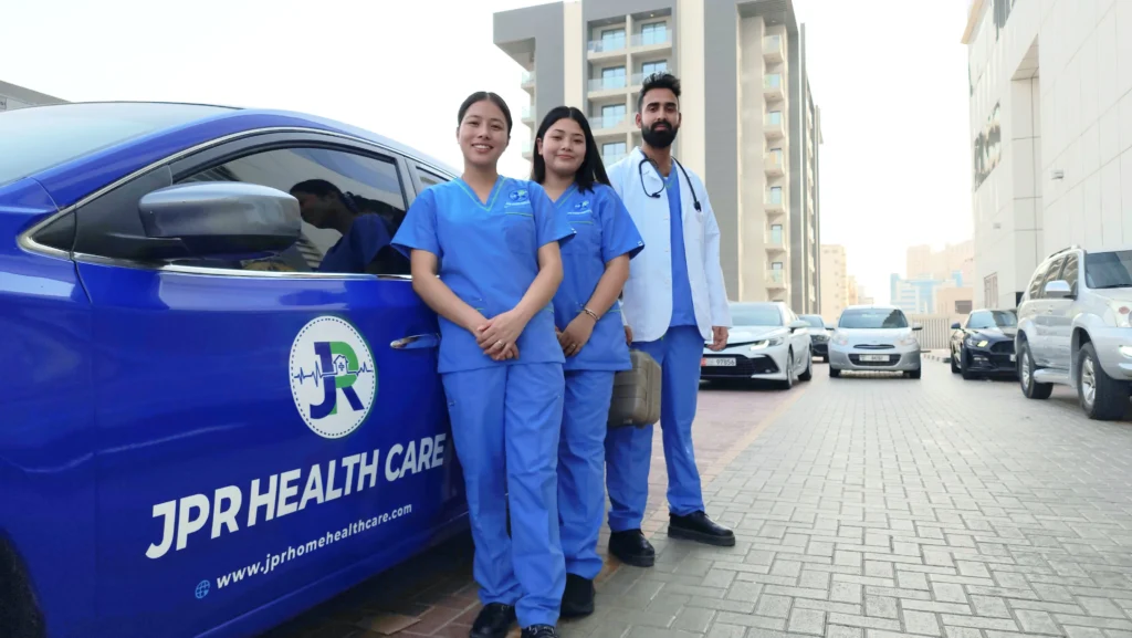 Group of JPR Home Healthcare nurses with doctor standing by a branded car, ready for elderly care service in Dubai.