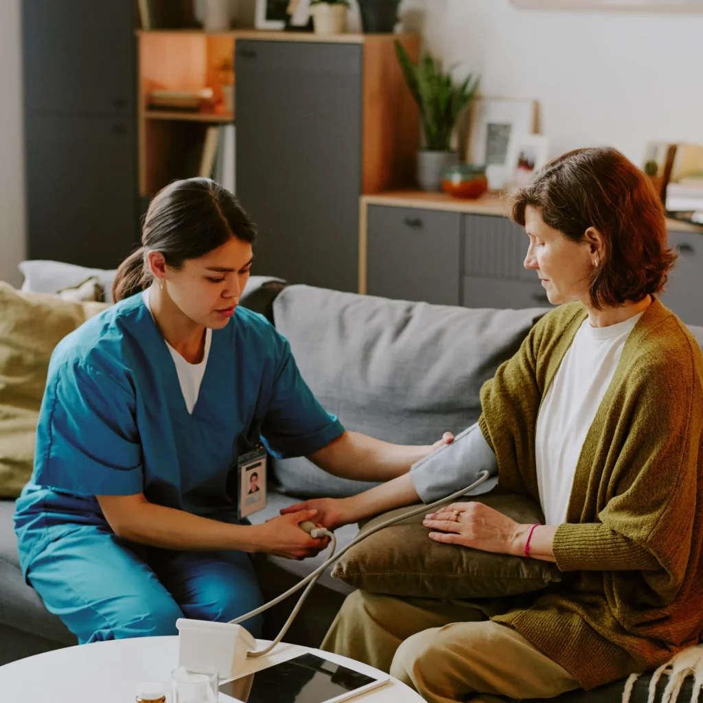 A home nurse performing a blood pressure check on a patient, delivering quality home health care services in Dubai